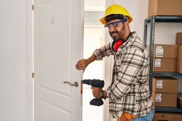 Young hispanic man worker smiling confident repairing door at home