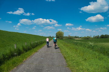 Radfahrer auf dem Weg von Papenburg nach Leer im Fr&uuml;hjahr. Aufnahme aus dem Fr&uuml;hjahr mit Blick in die Weite des Emslandes und auf den Deich der Ems in Norddeutschland