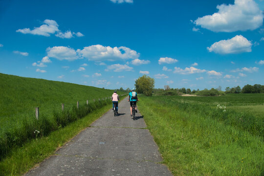 Radfahrer auf dem Weg von Papenburg nach Leer im Frühjahr. Aufnahme aus dem Frühjahr mit Blick in die Weite des Emslandes und auf den Deich der Ems in Norddeutschland