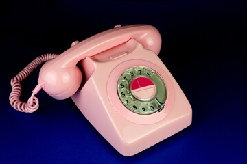 Vintage Pink Telephone on a Blue Table Surface