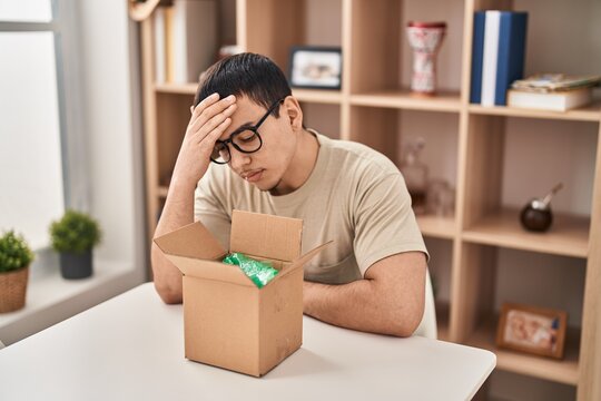 Young arab man with open gift in cardboard box surprised with hand on head for mistake, remember error. forgot, bad memory concept.