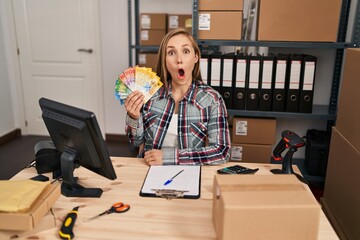 Young blonde doctor woman working at small business ecommerce holding swiss francs scared and amazed with open mouth for surprise, disbelief face