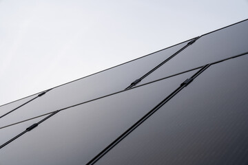 Diese PV-Anlage auf dem Dach einer modernen Wohnanlage nutzt die Kraft der Sonne, um erneuerbare Energie zu erzeugen. Die Solarpanels fangen das Sonnenlicht ein und wandeln es in saubere, grüne Energi - obrazy, fototapety, plakaty