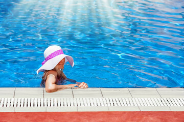 happy girl in a hat by the pool on the nature of the sea shore