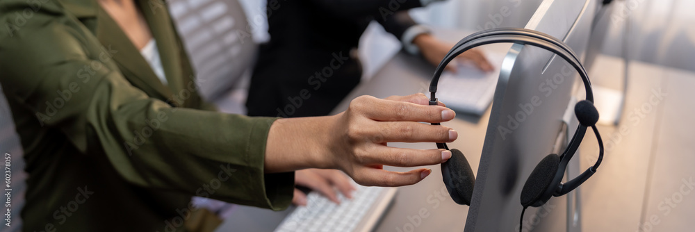 Aufkleber panorama focus hand holding headset on call center workspace desk with blur background of operator t