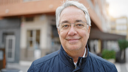 Middle age man with grey hair smiling confident at street