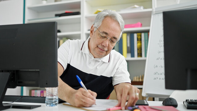 Middle Age Man With Grey Hair Teacher Using Computer Taking Notes At University Classroom