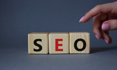 SEO - Search Engine Optimization symbol. Wooden blocks with words SEO. Businessman hand. Beautiful...