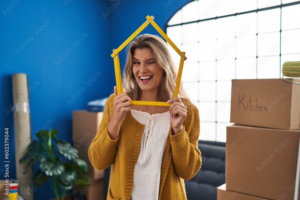 Poster young woman standing at new home winking looking at the camera with sexy expression, cheerful and ha