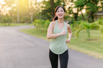 Fit Asian young woman jogging in park smiling happy running and enjoying a healthy outdoor...