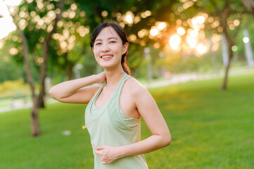 Female jogger. Fit young Asian woman with green sportswear stretching muscle in park before running and enjoying a healthy outdoor. Fitness runner girl in public park. Wellness being concept