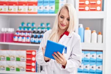 Young blonde woman pharmacist using touchpad working at pharmacy