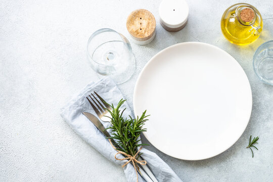 White plate, shaker, wine glass and cutlery on stone table. Table setting, flat lay image with copy space.