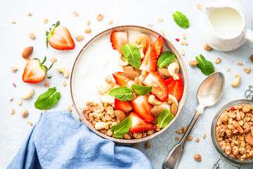 Yogurt with granola and strawberries on white. Healthy snack or breakfast, fruit salad. Top view.