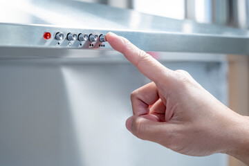 Male hand pushes the button of extractor fan on the cooker hood. Home appliance in domestic kitchen.