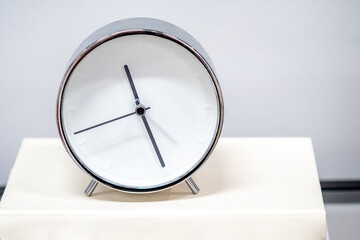Time management concept. Modern silver alarm clock on the book.