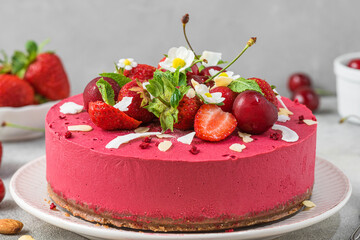 Raw vegan strawberry and cherry cashews cake with fresh berries, nuts and flowers. Veggie dessert