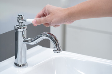 Save water concept. Hand closing stainless steel water tap or chrome faucet in the bathroom.