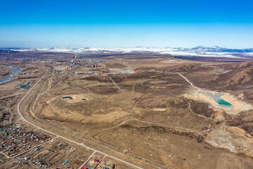 Aerial mountain river with green vegetation on shore flows among huge lifeless brown rocks. . Wide panoramic shot