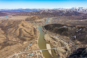Aerial mountain river with green vegetation on shore flows among huge lifeless brown rocks. . Wide panoramic shot