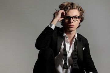 elegant young man looking up and adjusting eyeglasses