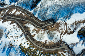 Car drive in sunny winter day on road in mountain range aerial view. Perspective on ridge of Altai Mountains. Northern Kazakhstan