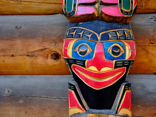 A colorful totem pole decorates the entrance to a 1st Nations People Tribal area in the Yukon Territory - 602388425