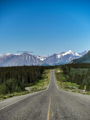The paved portion of the Alaska Highway and snow covered mountains in the Yukon Territory