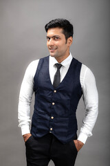 Fototapeta premium Studio shot of cheerful, young, handsome Indian business man in formal wear against grey background. Male model. Fashion Portrait.