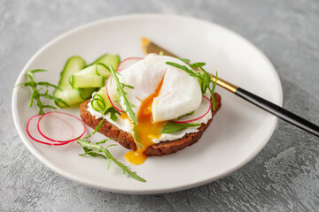 Open sandwich with vegetables and poached egg in a plate on the table