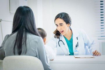 Pediatrician giving advice to mother of sick little girl at hospital.