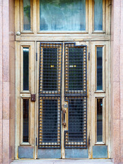 Old tall doors with a numerical lock, the glass of which is closed with a powerful lattice of reinforcement