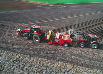 Modernste Landtechnick bei der Kartoffelbestellung - Drohnenfoto - Kartoffellegemaschine wird mit...
