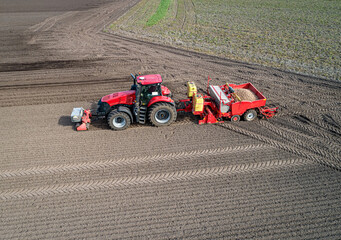 Luftbild - Seitenansicht von oben, moderne Landtechnik bei der Kartoffelpflanzung - Roter Traktor...