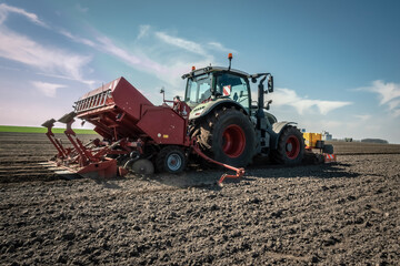 Obraz premium Karoffelpflanzmaschine im Frühjahr auf dem Kartoffelfeld im Einsatz - Gegenlichtaufnahme.
