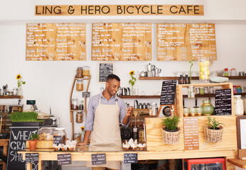 Black man, cafe sign and phone of an entrepreneur with happiness from small business. Coffee shop, mobile and African barista looking on an app with a smile at bakery and restaurant feeling happy