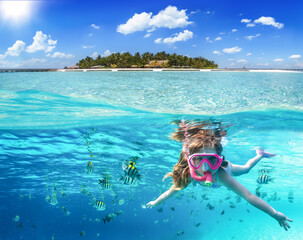Split image with a tropical island and underwater life with a girl snorkeling in the ocean of the Maldives with colorful fish - obrazy, fototapety, plakaty