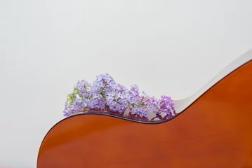 Schilderijen op glas A classic guitar with purple lilac flowers on it © Dana