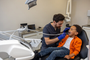 Obraz premium Male dentist working with dark-skinned boy