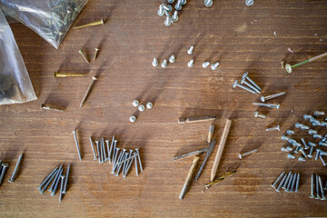 screws and self-tapping screws of various lengths on a wooden table. close-up.