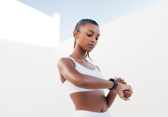 Confident female athlete checking her pulse. Healthy woman in a white sports bra looking on...