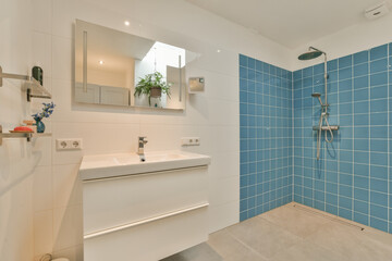 a bathroom with blue tiles on the walls and white fixtures in the shower stall is next to the bathtub