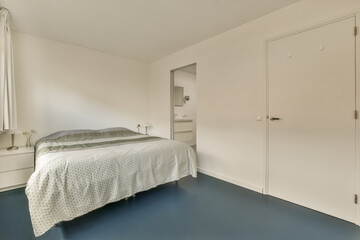 Fototapeta na wymiar a bedroom with white walls and blue flooring the room has a bed in it is next to an open door