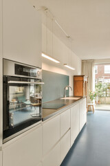 a modern kitchen with white cabinets and blue flooring in the center of the image is an open door leading to a patio