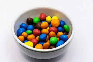 Colorful chocolate in a bowl isolated on white background.