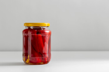 food, eating and preserve concept - close up of jar with pickled red hot chili peppers on table
