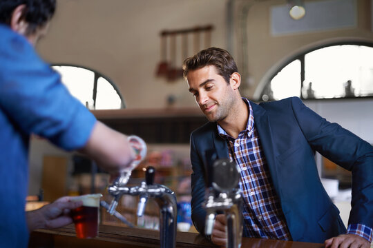 Professional man at pub, order beer and relax on a break, leaning against countertop in bistro with alcohol drink. Hospitality industry, male business person at restaurant and enjoying social time