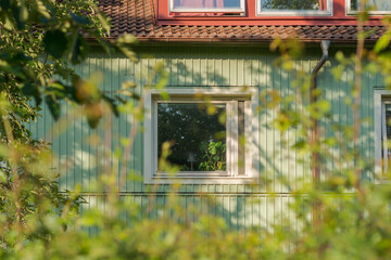 Gothenburg, Sweden - June 13, 2020: Beautiful green terraced house in Sweden with a closed window on Hisingen in Gothenburg at summertime.