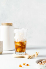 Black coffee with ice and cream in a tall glass. Coffee beans. 