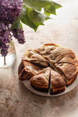 Chocolate cheesecake layered with brownie and cottage cheese. Chocolate cake sliced on brown textured background with lilac flowers rustic style. Still life